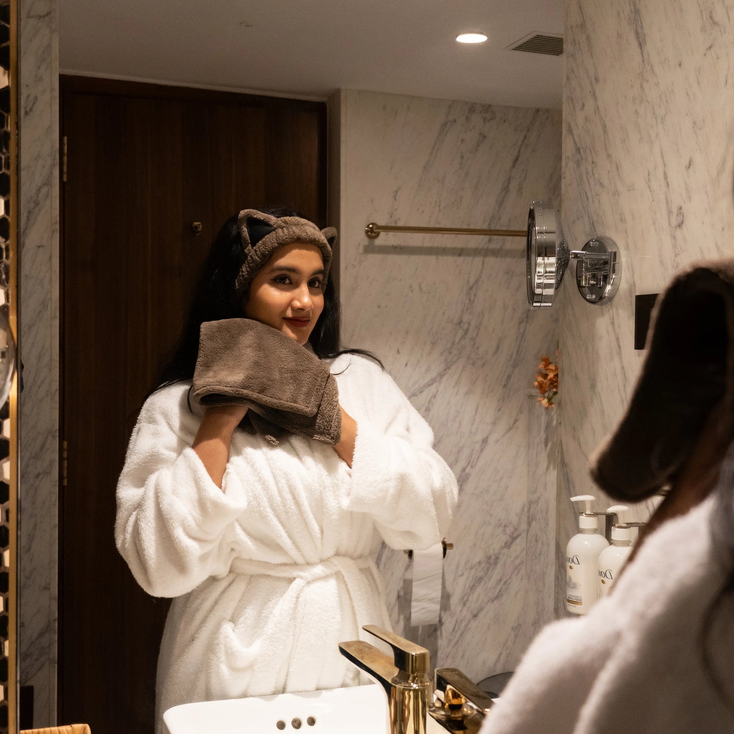 Woman using brown Kitty Bloom combo set in a bathroom mirror scene.