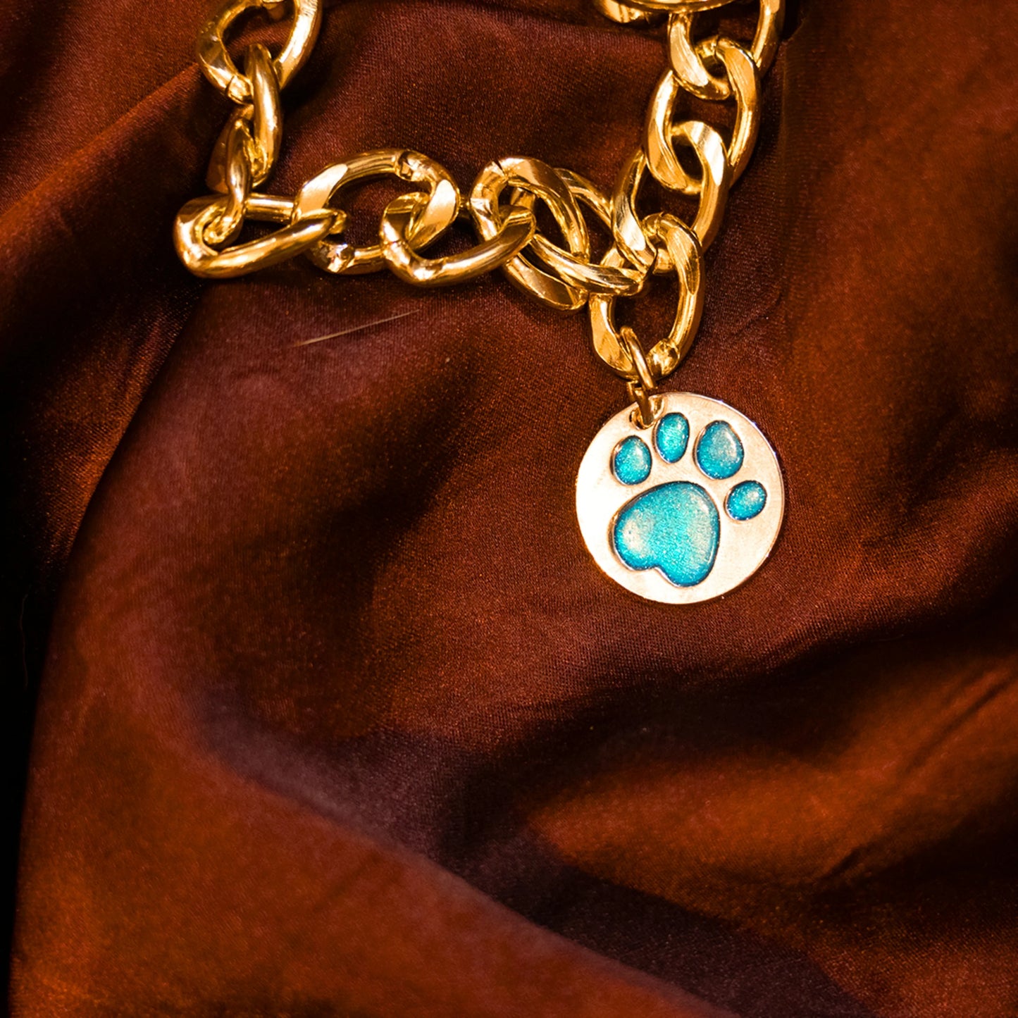 Close-up of glitter paw blue pendant on gold chain collar