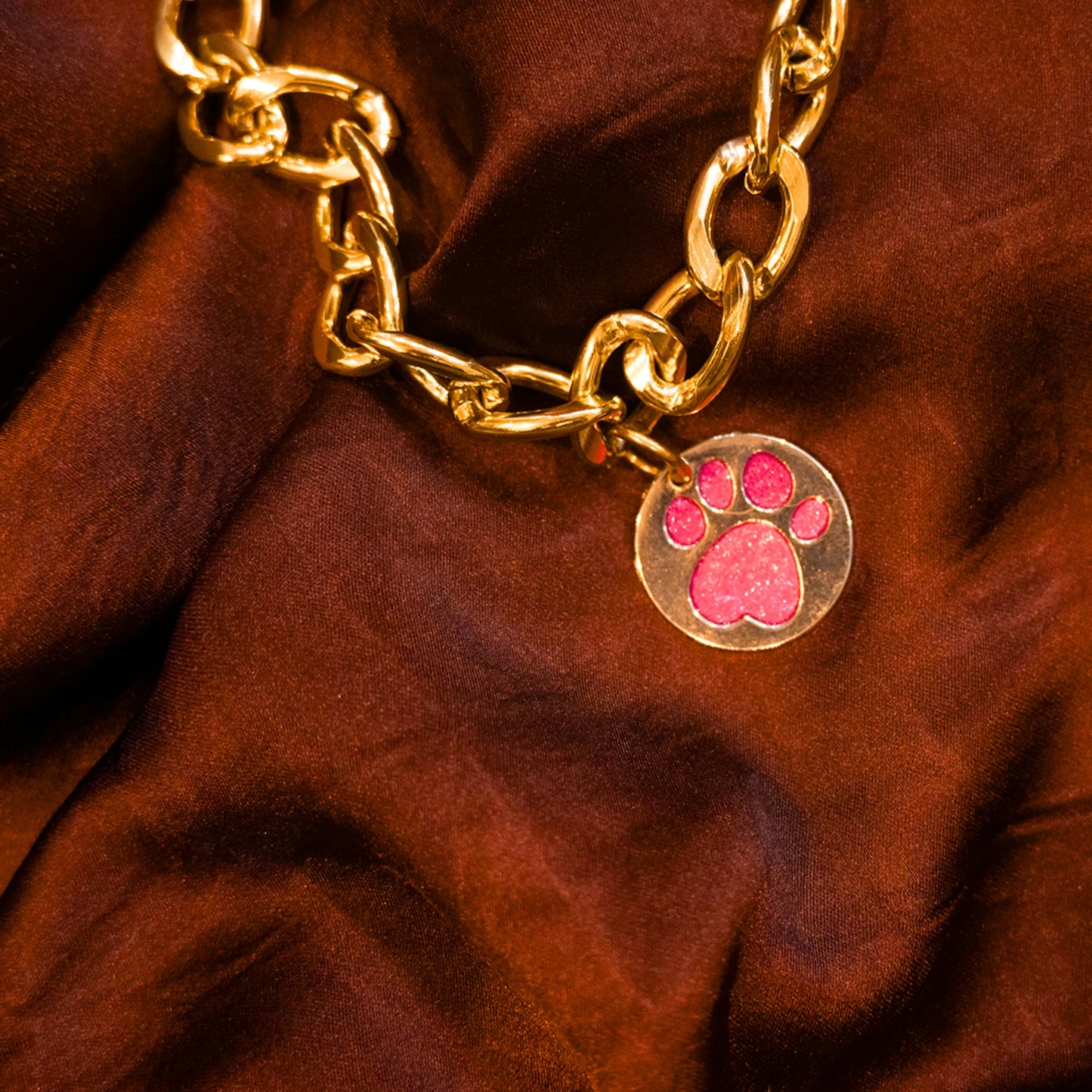 Close-up of glitter paw pink pendant on gold chain collar