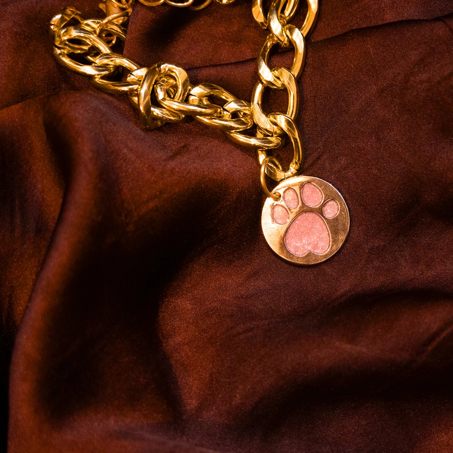Close-up of glitter paw baby pink pendant on gold chain collar