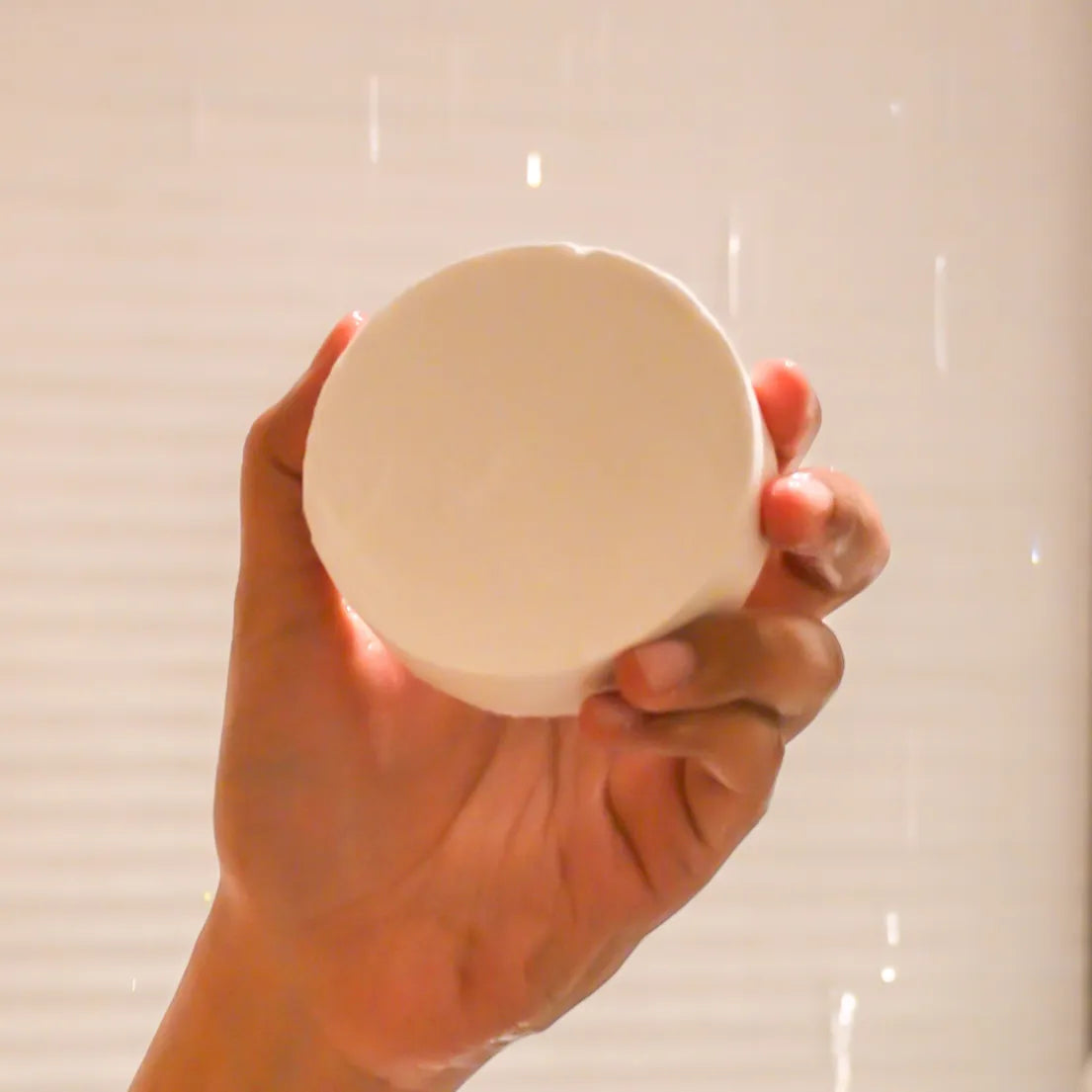 Person holding compressed towel while shower runs on back.
