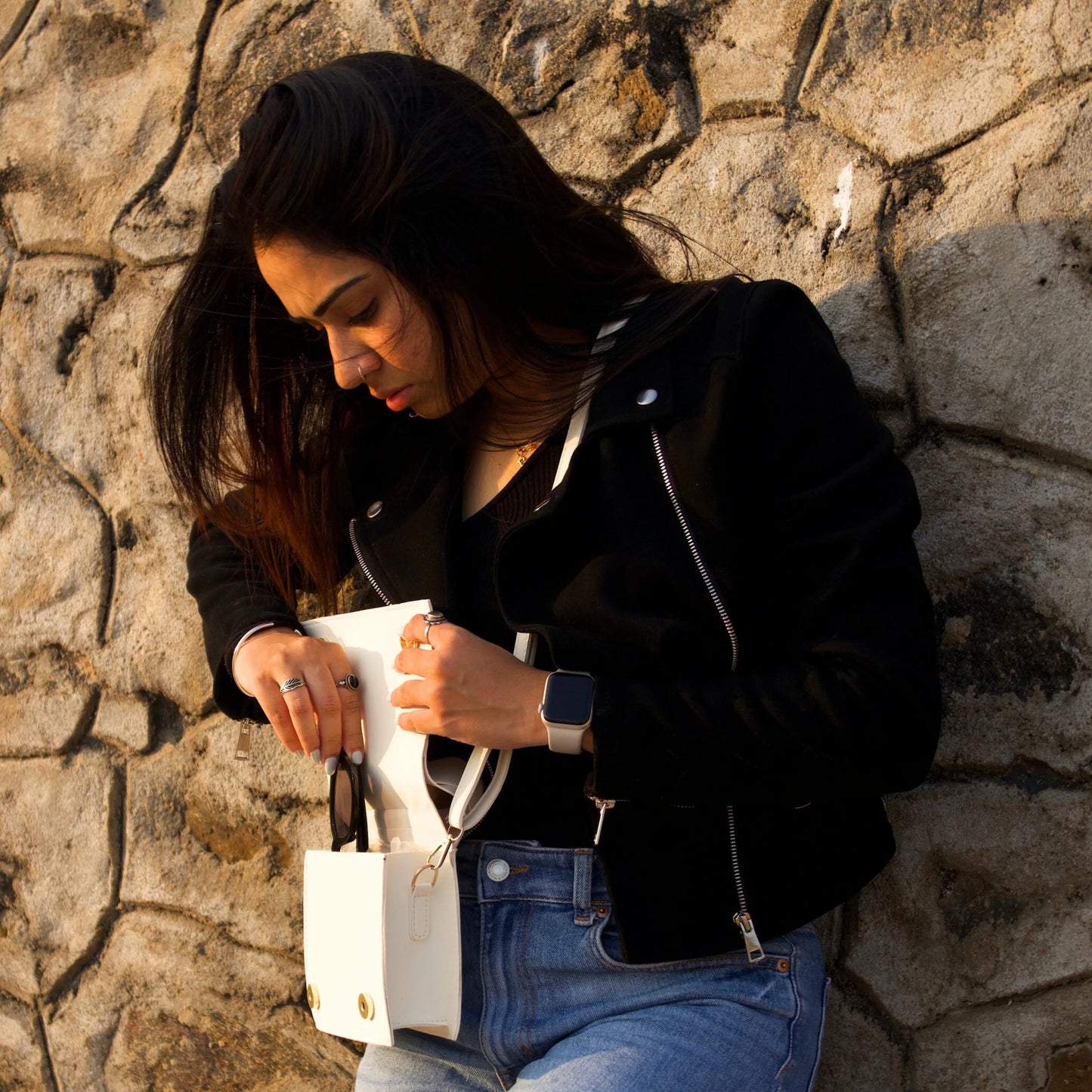 Woman placing sunglasses in the white jacket-inspired handbag