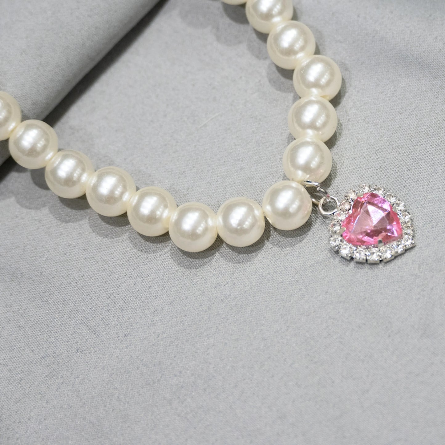 Close-up of pink gemstone charm on grey background