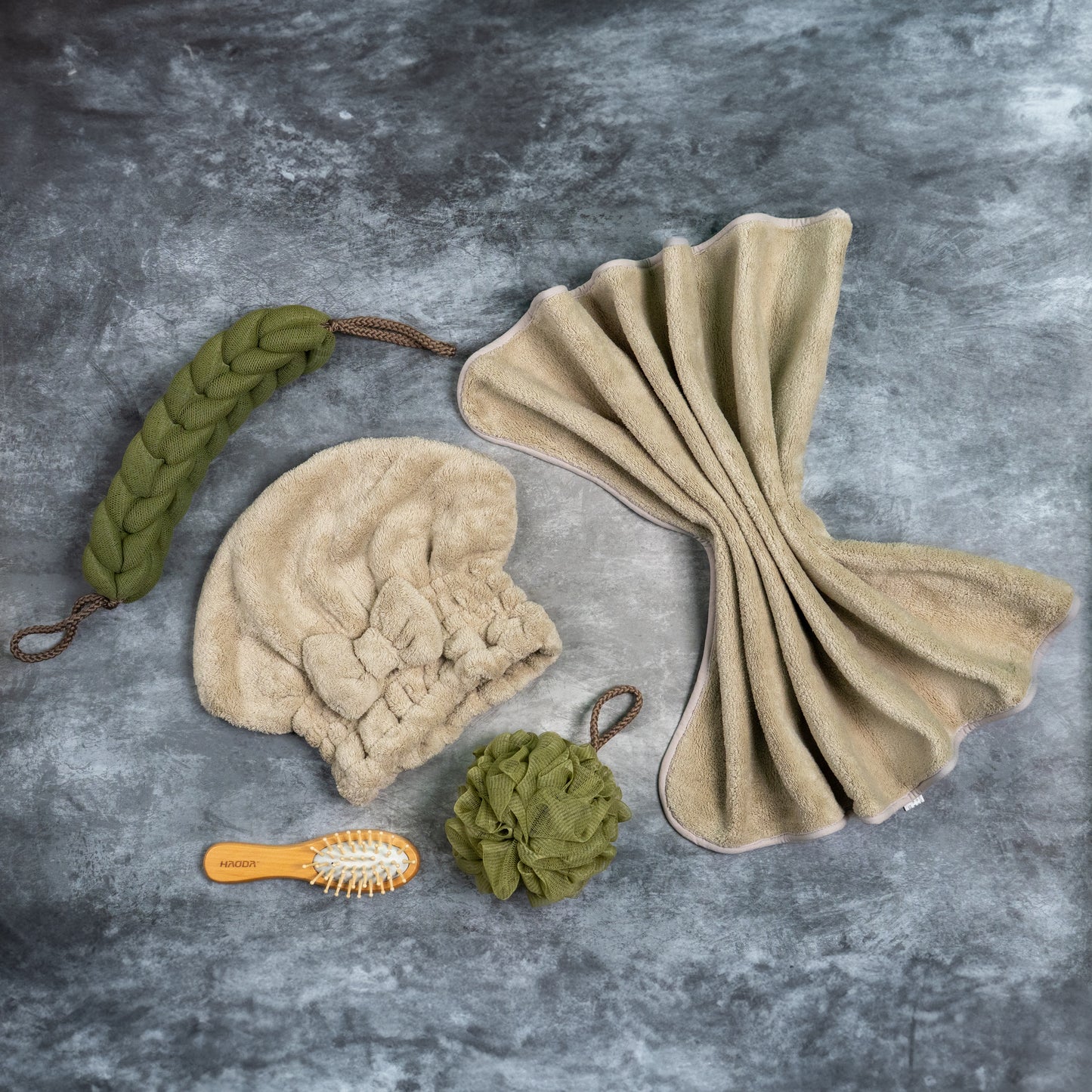 Flat lay of green Soothe Luxe Ribbon Bow Shower Kit including towel, head wrap, loofah, and hairbrush