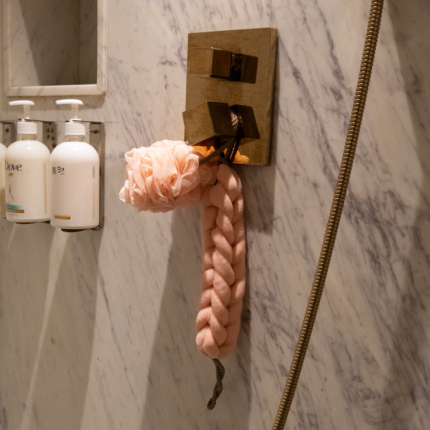 Detailed view of pink braided scrubber, soft hair towel, and exfoliating loofah