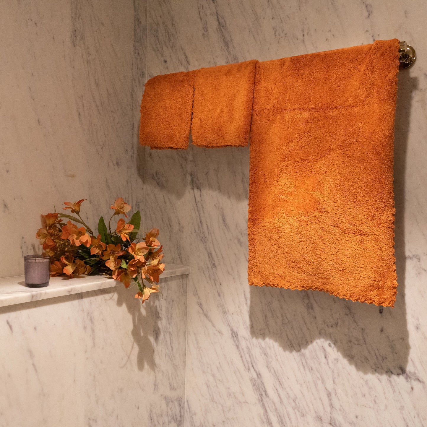 Trio of orange Loom Touch towels displayed flat with textured detailing visible