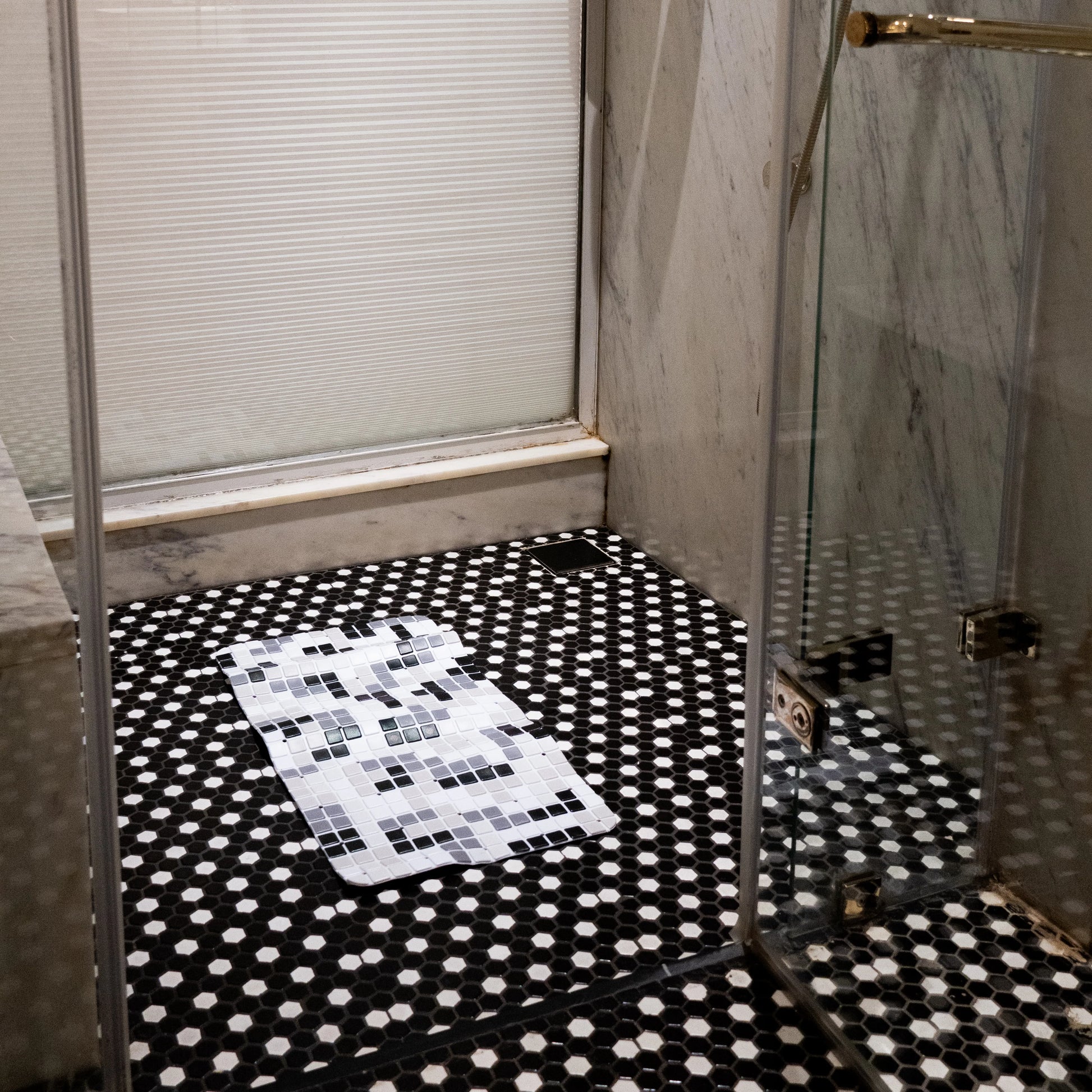 Black-white mat placed inside shower room on floor.
