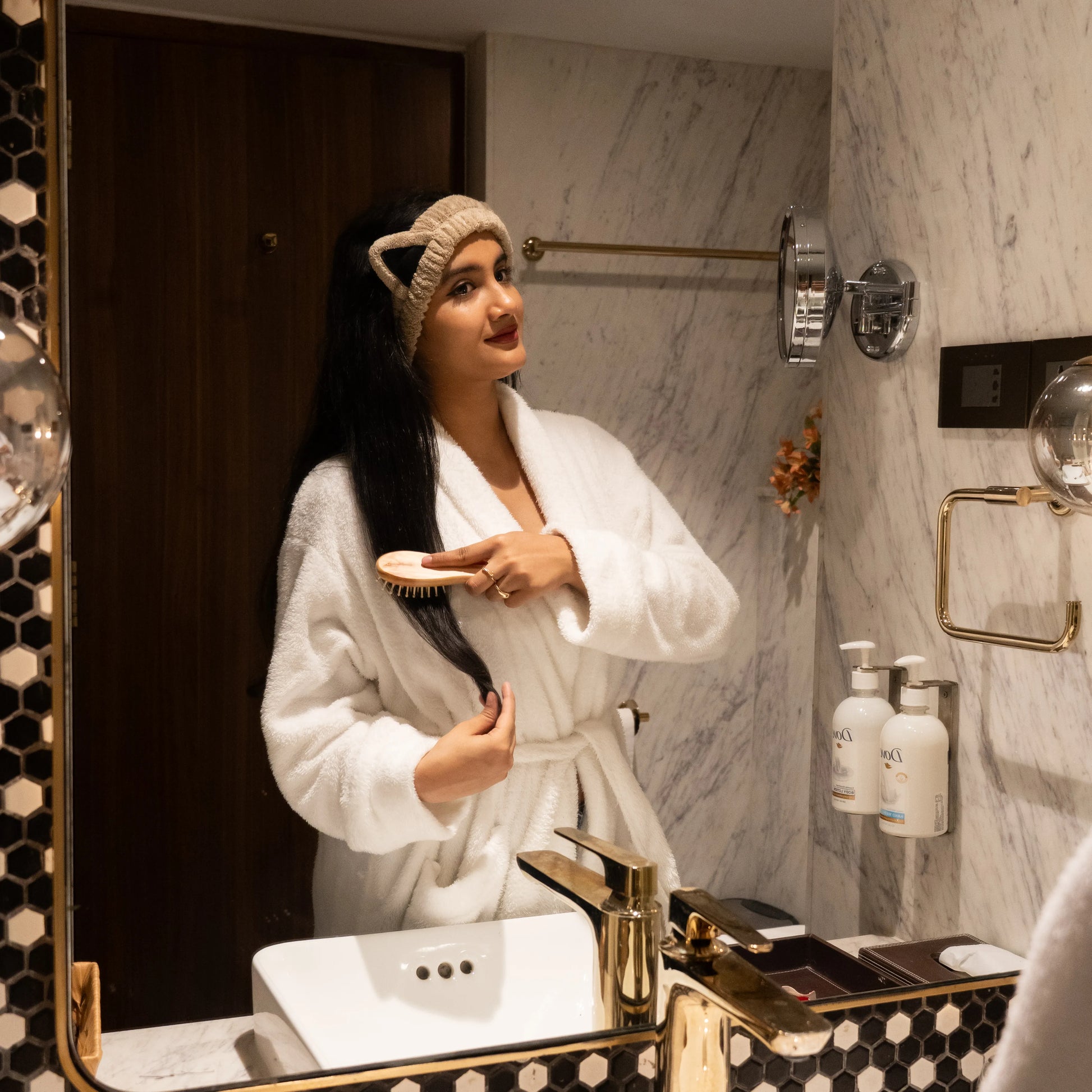 Woman using beige Kitty Bloom combo set in a bathroom mirror scene.
