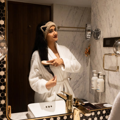 Woman using beige Kitty Bloom combo set in a bathroom mirror scene.