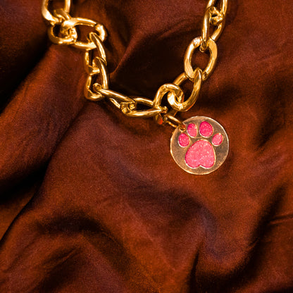 Close-up of glitter paw pink pendant on gold chain collar