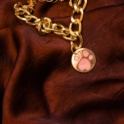 Close-up of glitter paw baby pink pendant on gold chain collar
