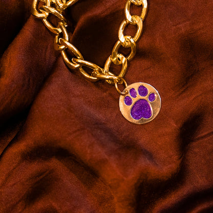 Close-up of glitter paw purple pendant on gold chain collar