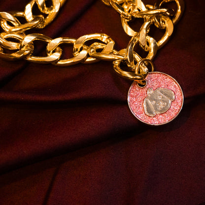 Gold pet necklace with white glitter dog-face charm displayed on a maroon cloth background