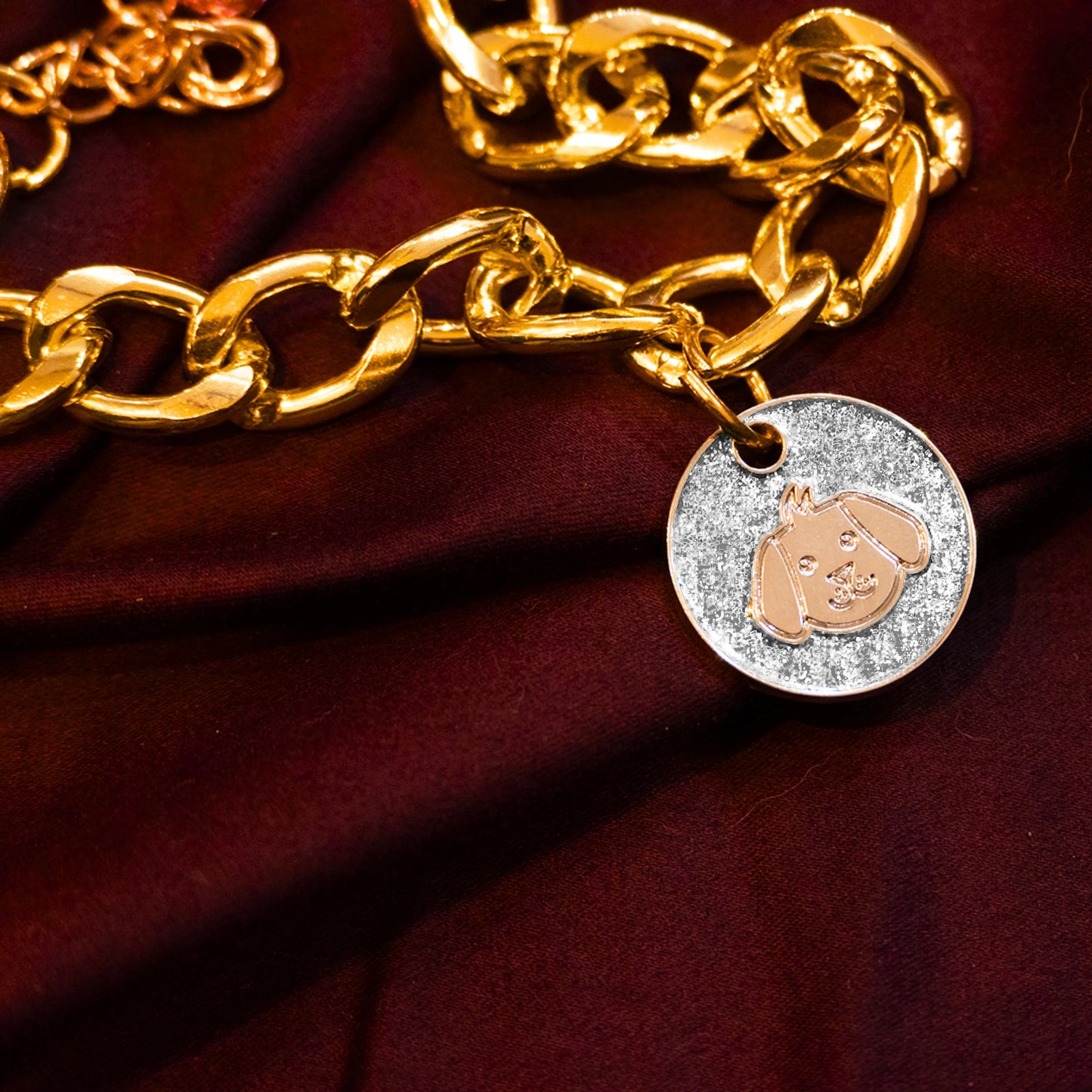 Gold pet necklace with white glitter dog-face charm displayed on a maroon cloth background
