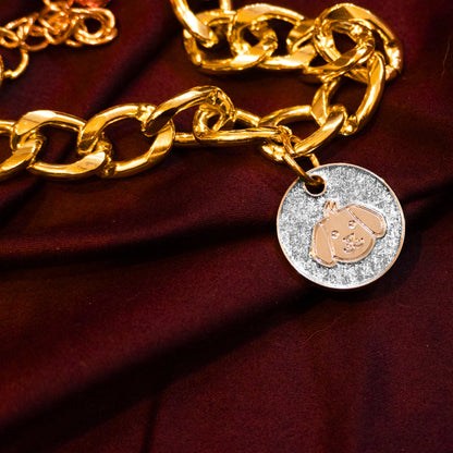 Gold pet necklace with white glitter dog-face charm displayed on a maroon cloth background