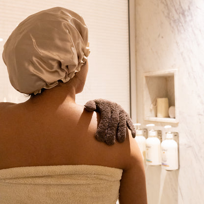 Close-up of light brown bath gloves with textured fabric and exfoliating accessories