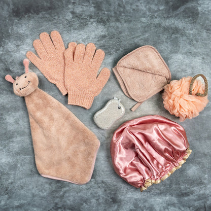 Peach-toned Luxe Bloom gloves displayed with pumice, loofah, and wooden brush