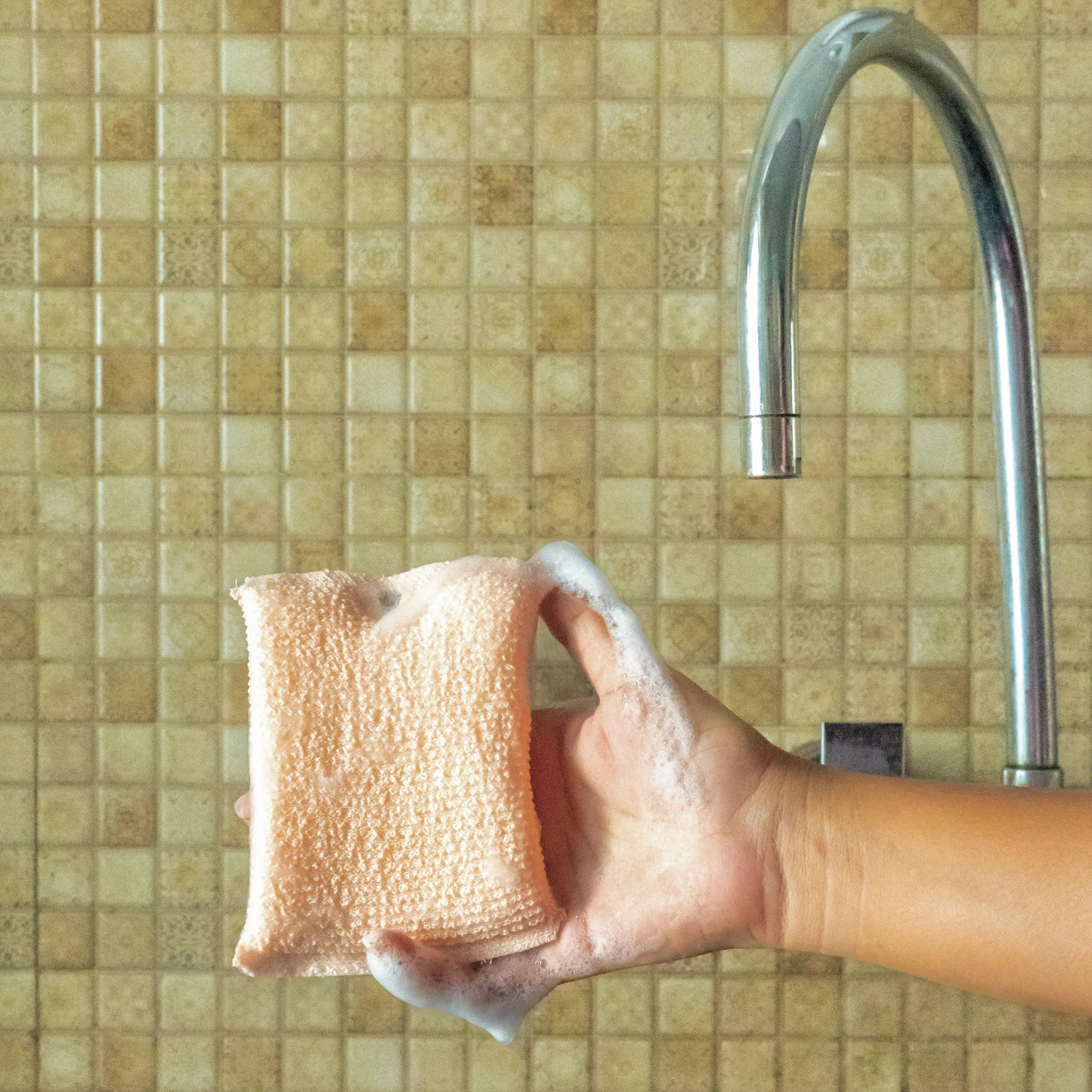Hand holding vibrant orange oil wipe.