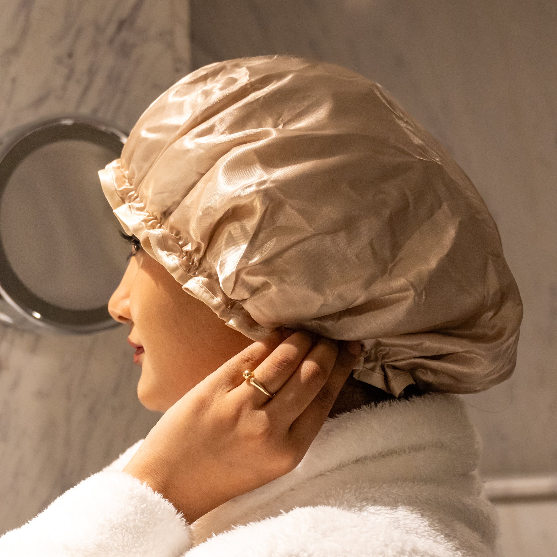 Woman wearing beige shower cap, head fully covered, angle 1.