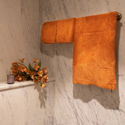 Trio of orange Loom Touch towels displayed flat with textured detailing visible