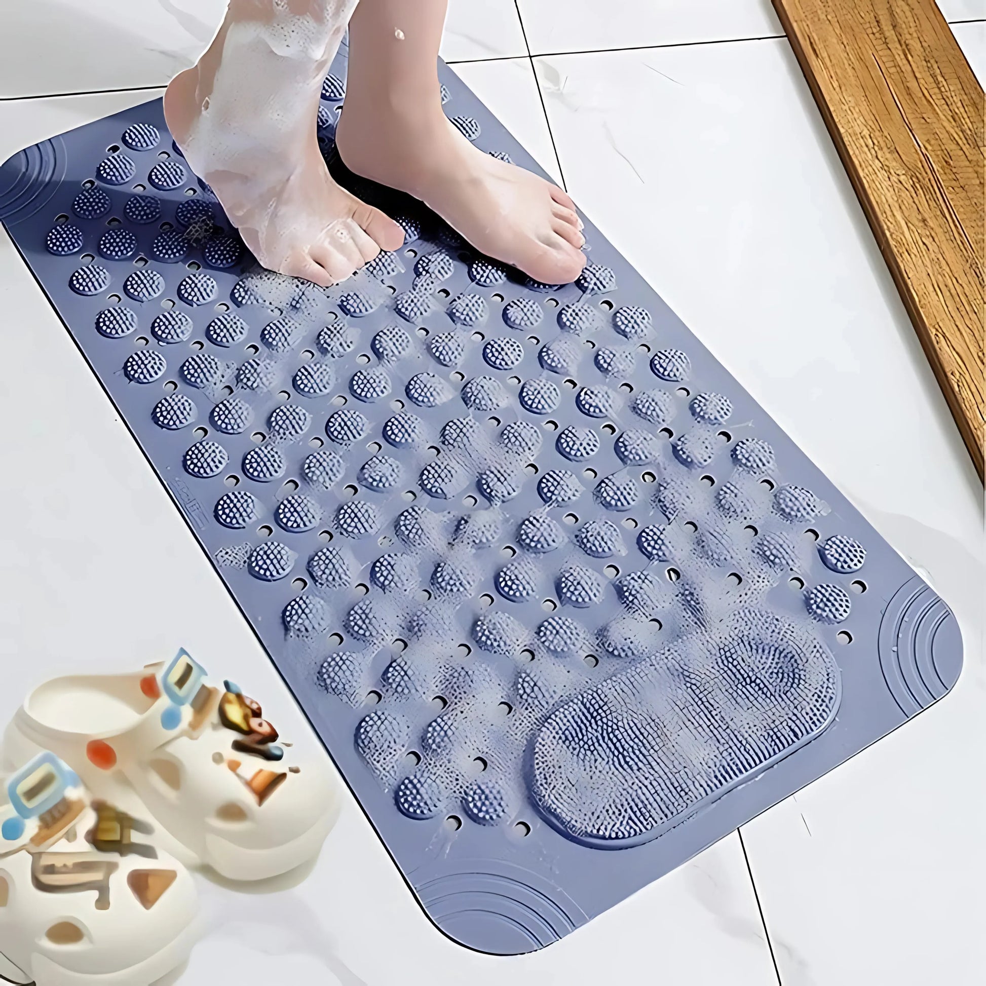 Person’s foot stepping on a textured blue bath mat with water flowing around.