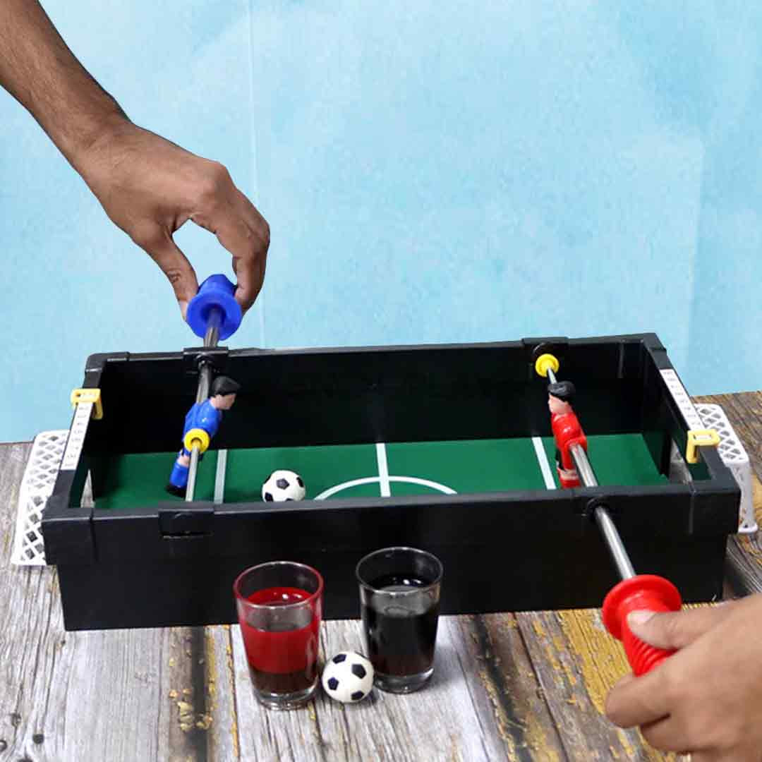 Unpacked foosball table setup with shot glasses and handles