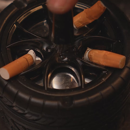Wheel-shaped ashtray with push-and-spin lid, cigarette resting on rim.