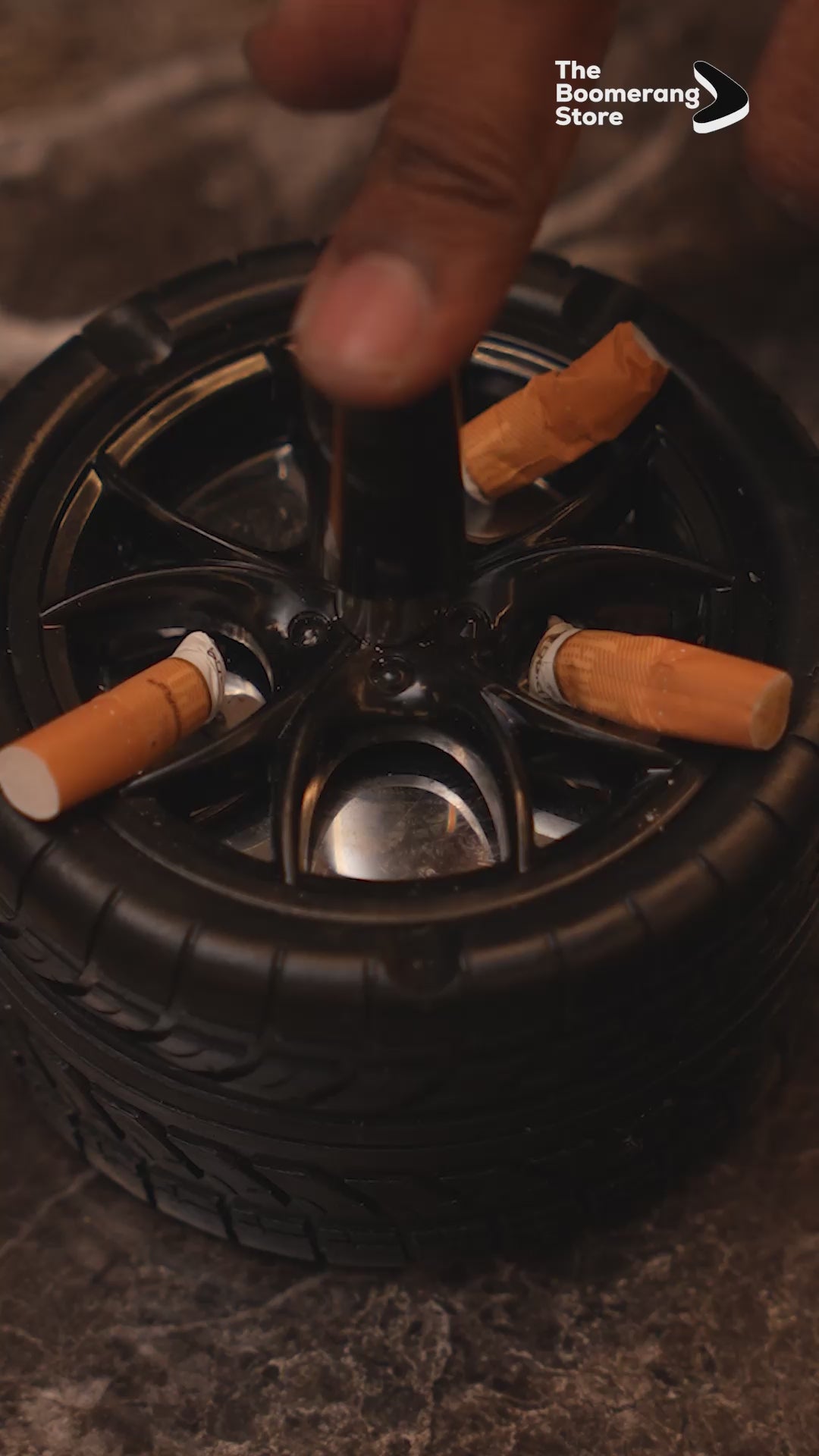 Wheel-shaped ashtray with push-and-spin lid, cigarette resting on rim.