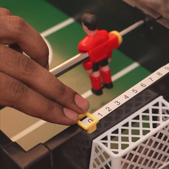 Small foosball drinking game set with player rods and two shot glasses.